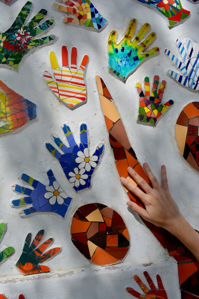 Colorful mosaic hand prints and abstract shapes create lively wall art.